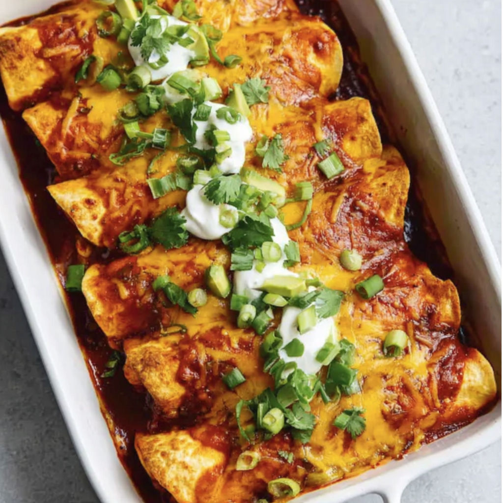 A dish of chicken enchiladas with white cheese and green onions.