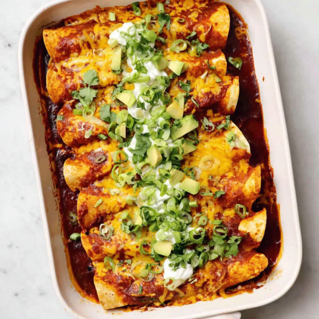 A dish of chicken enchiladas with avocado and sour cream.