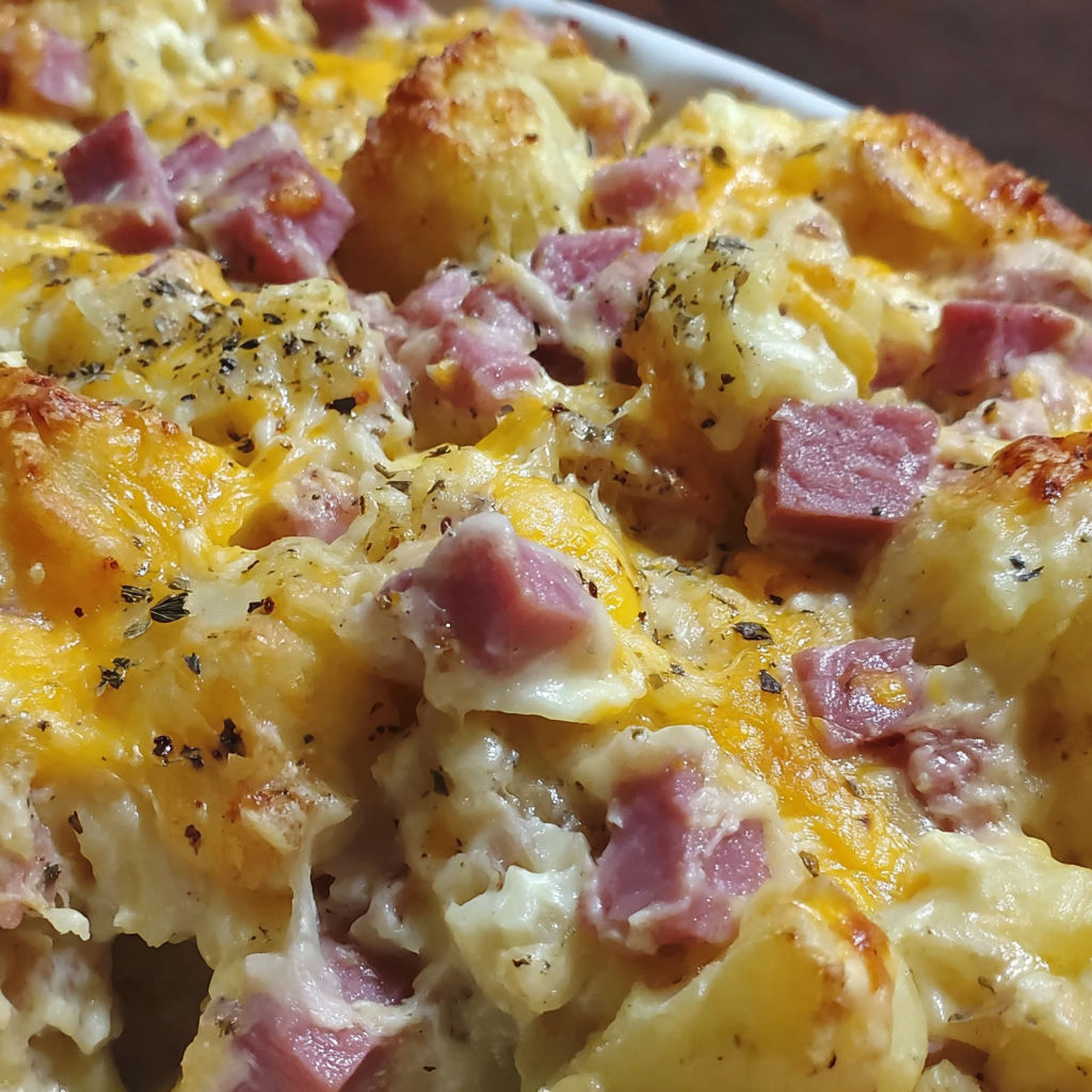 A close up of a cheesy ham potato casserole.