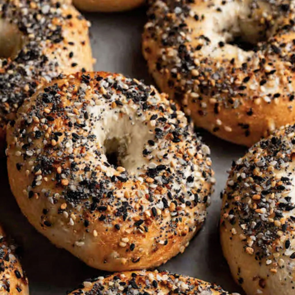 A pile of bagels with sesame seeds on top.