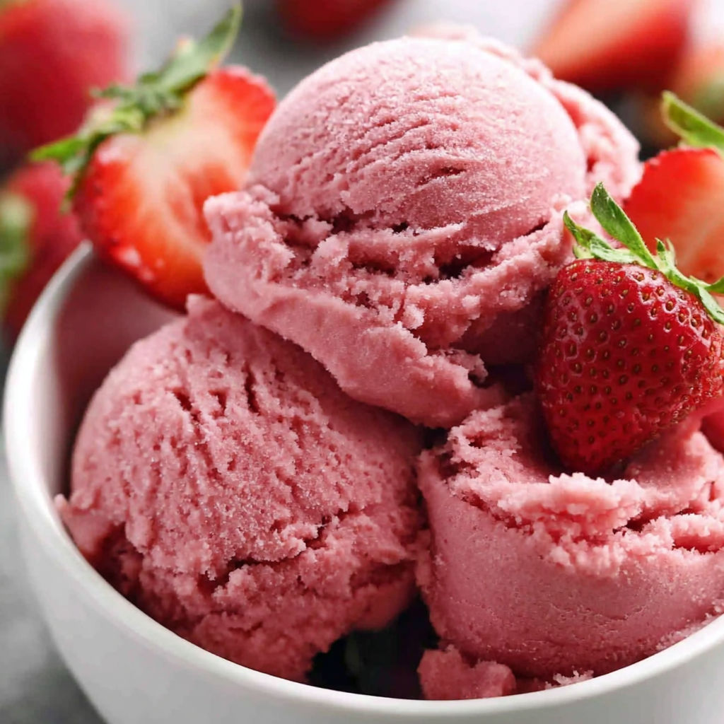 A bowl of pink sorbet with strawberries.