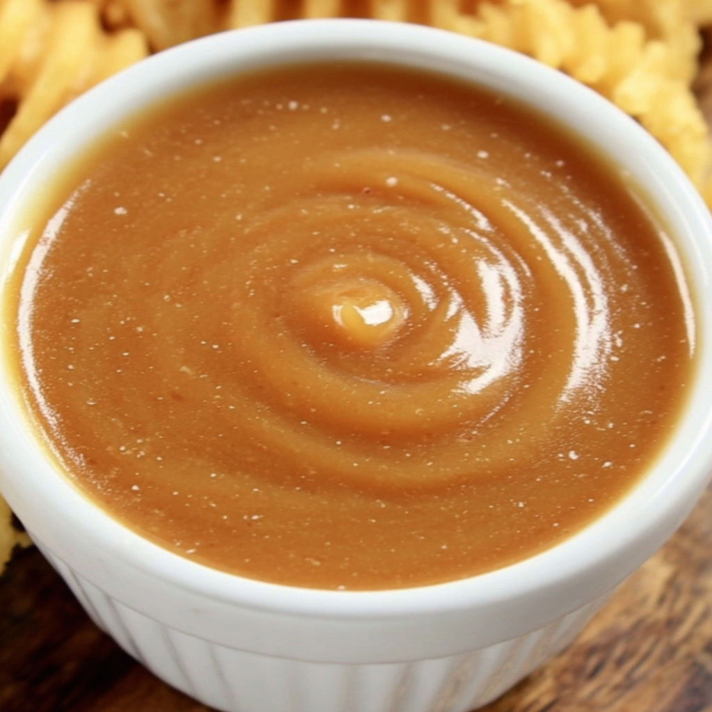 A bowl of sauce with a spoon in it.