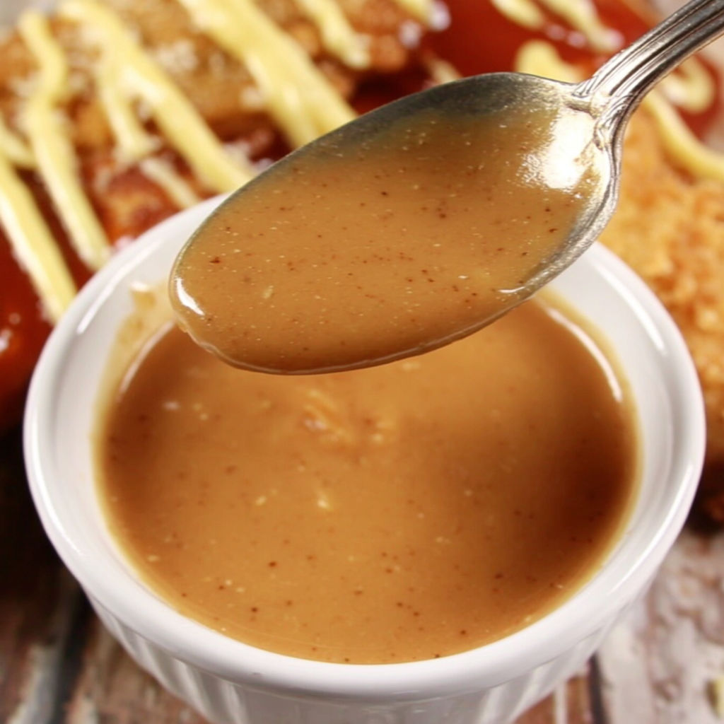A spoon is in a bowl of sauce.
