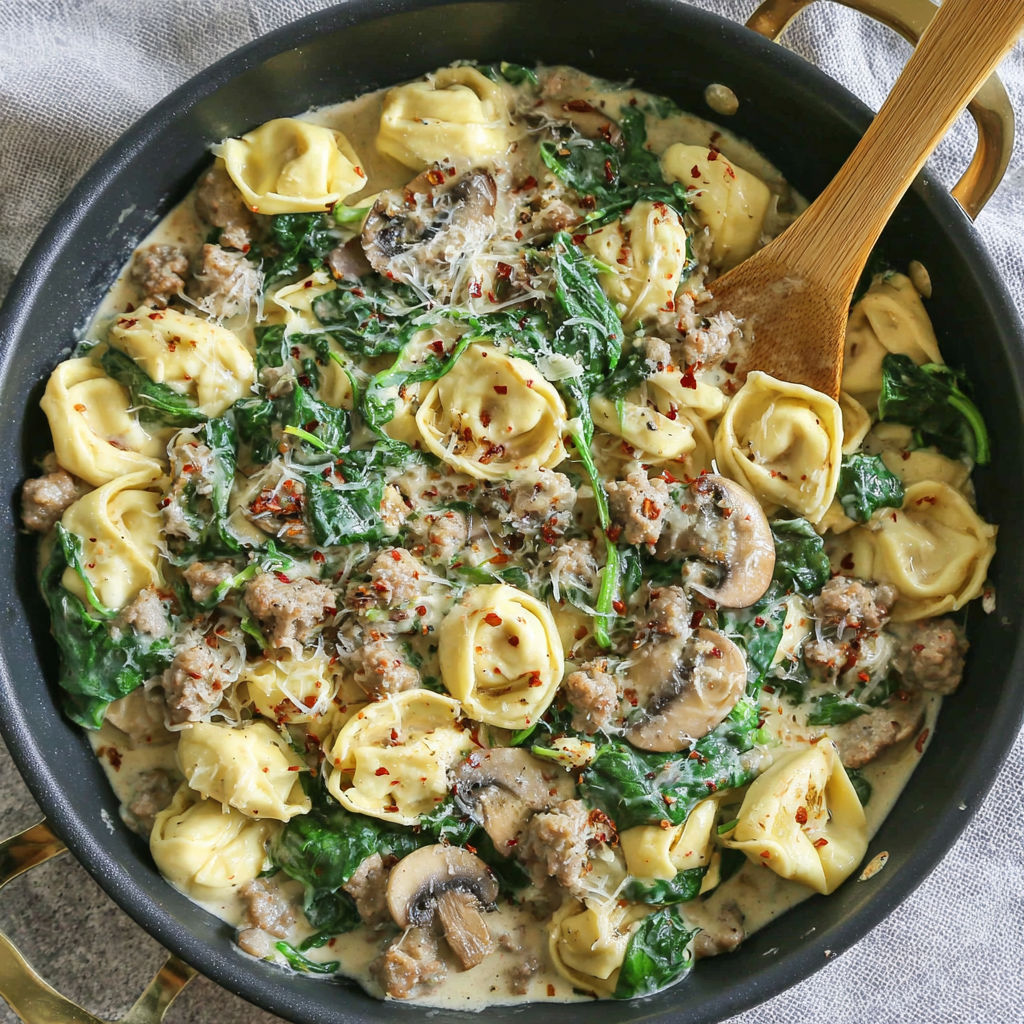 A bowl of pasta with mushrooms and spinach.