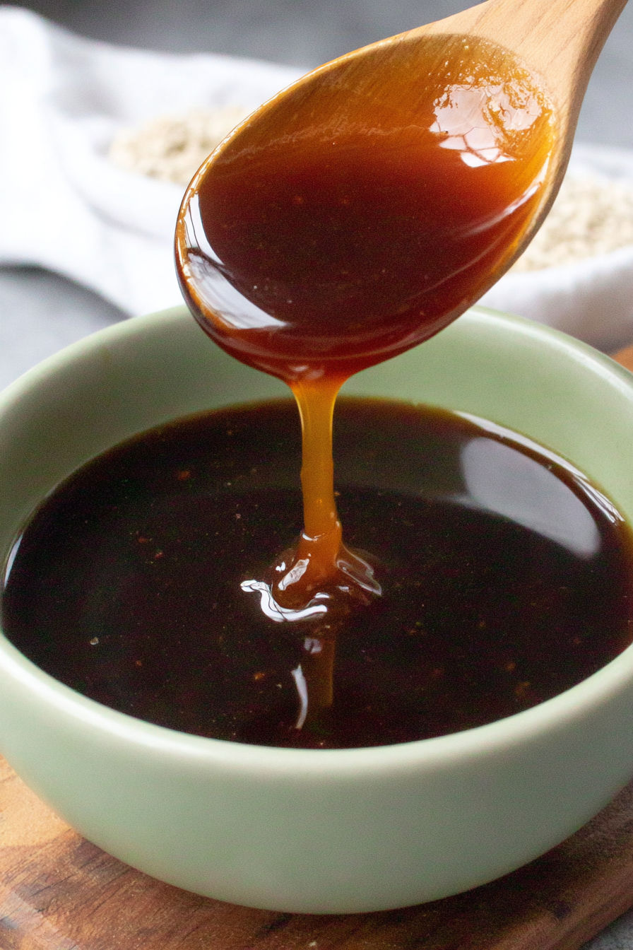 A spoon is in a bowl of sauce.