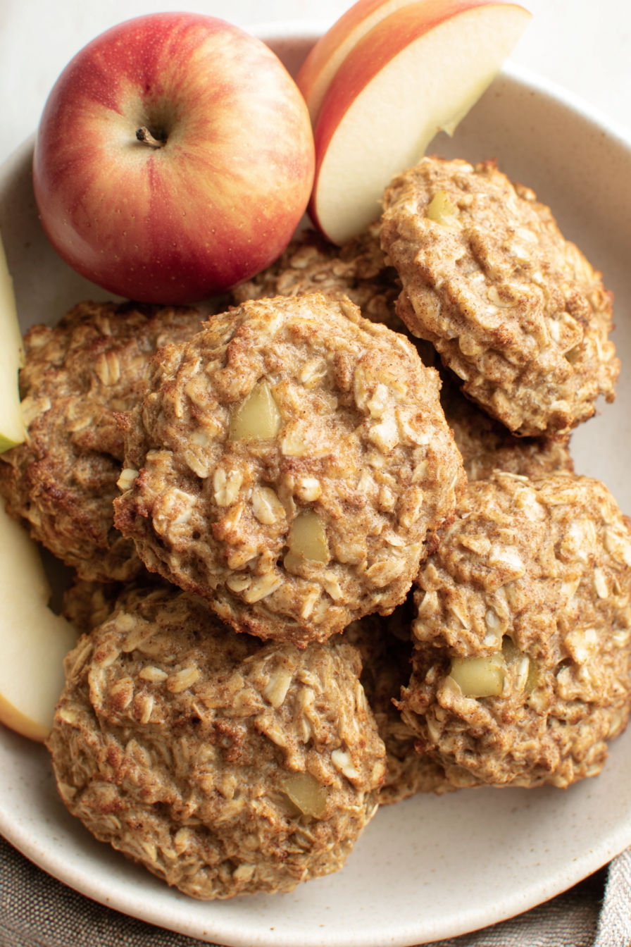 A plate of cookies with an apple on the side.