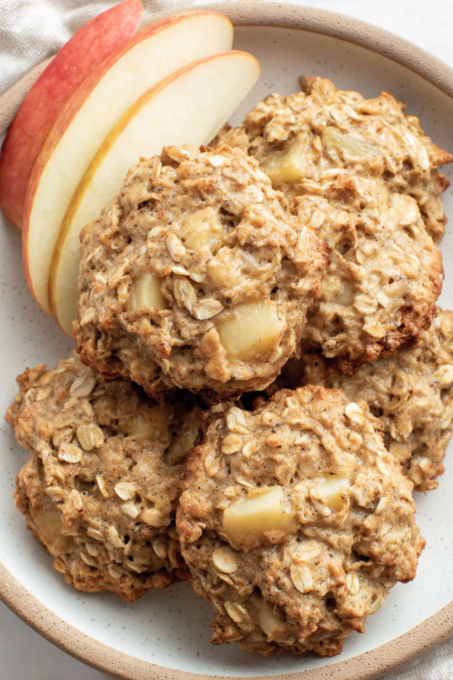 A plate of cookies with an apple on the side.