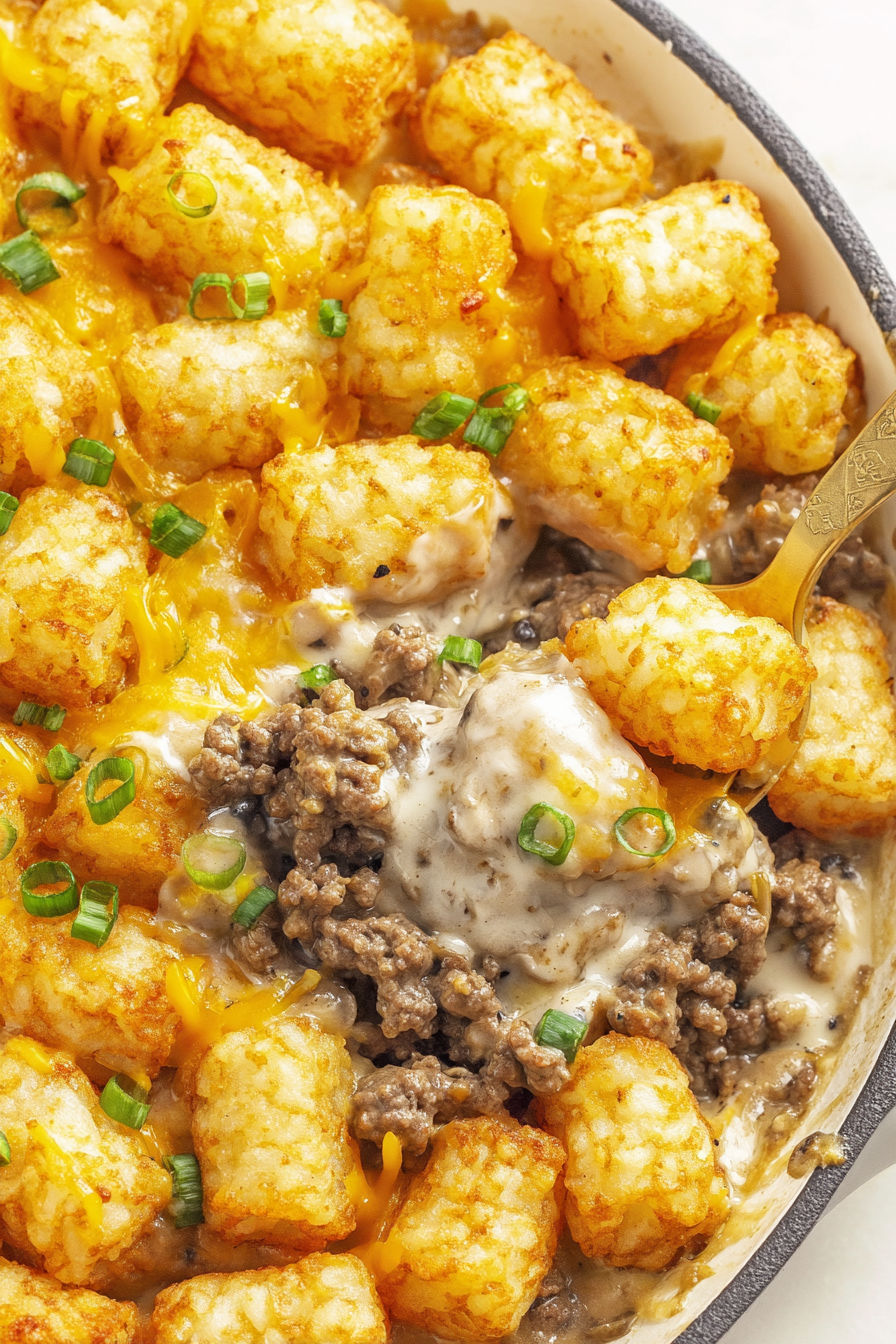 A bowl of tater tot casserole with cheese and meat.