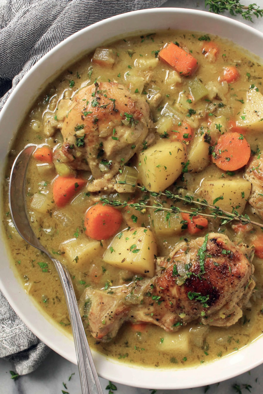 A plate of chicken stew with carrots and potatoes.