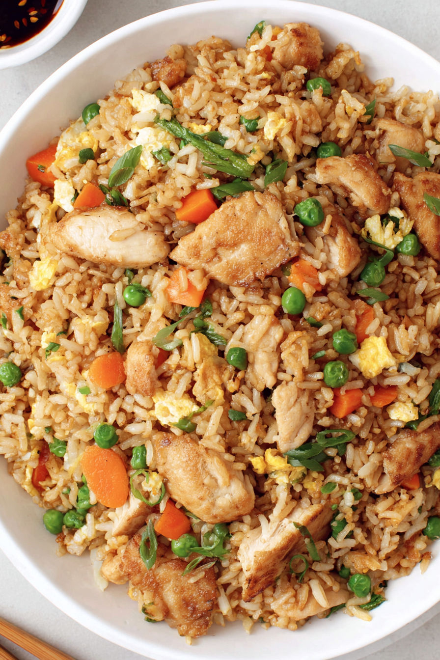 A bowl of rice with chicken and peas.