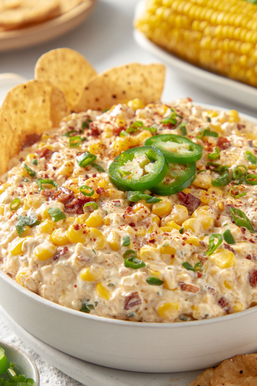 A bowl of Mexican street corn dip with jalapenos on top.