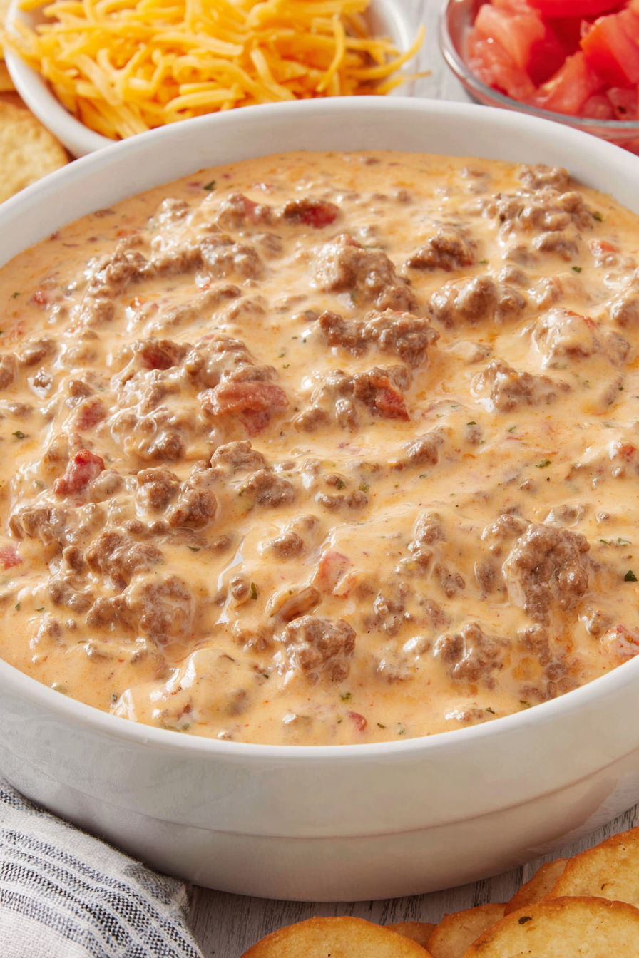 A bowl of chili with meat and tomatoes.