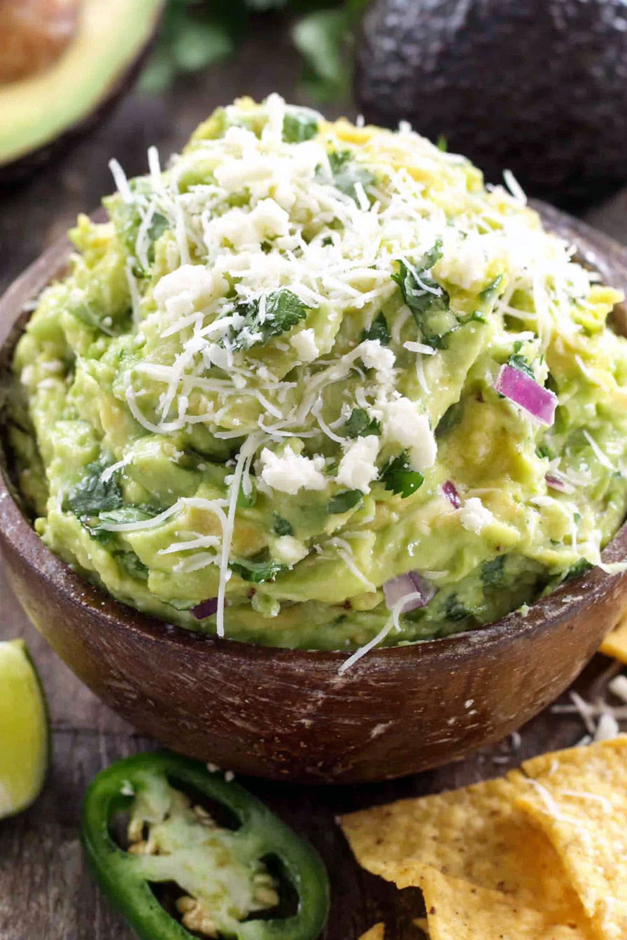 A bowl of guacamole with cheese on top.