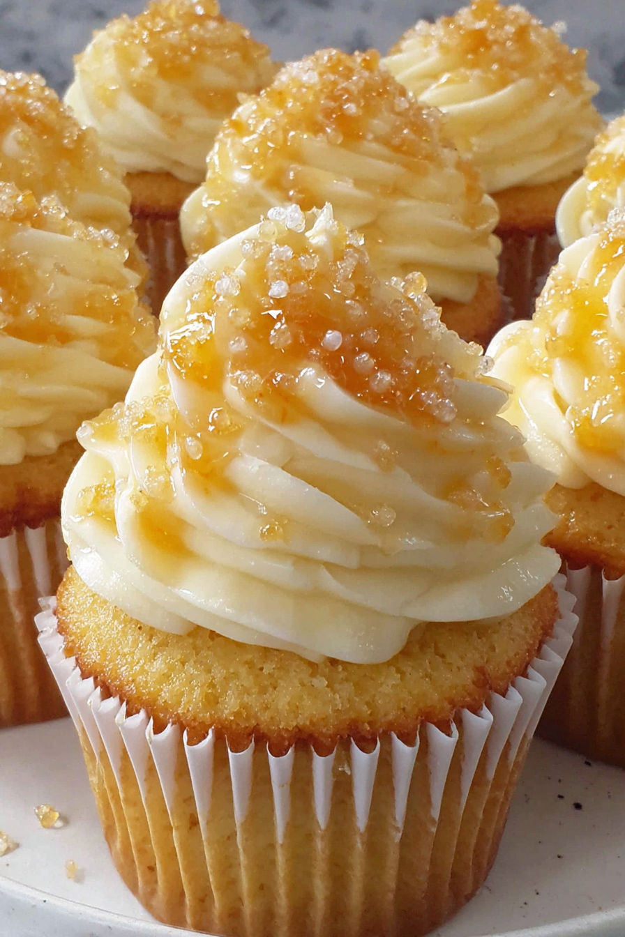 A cupcake with a yellow frosting and a sprinkle on top.