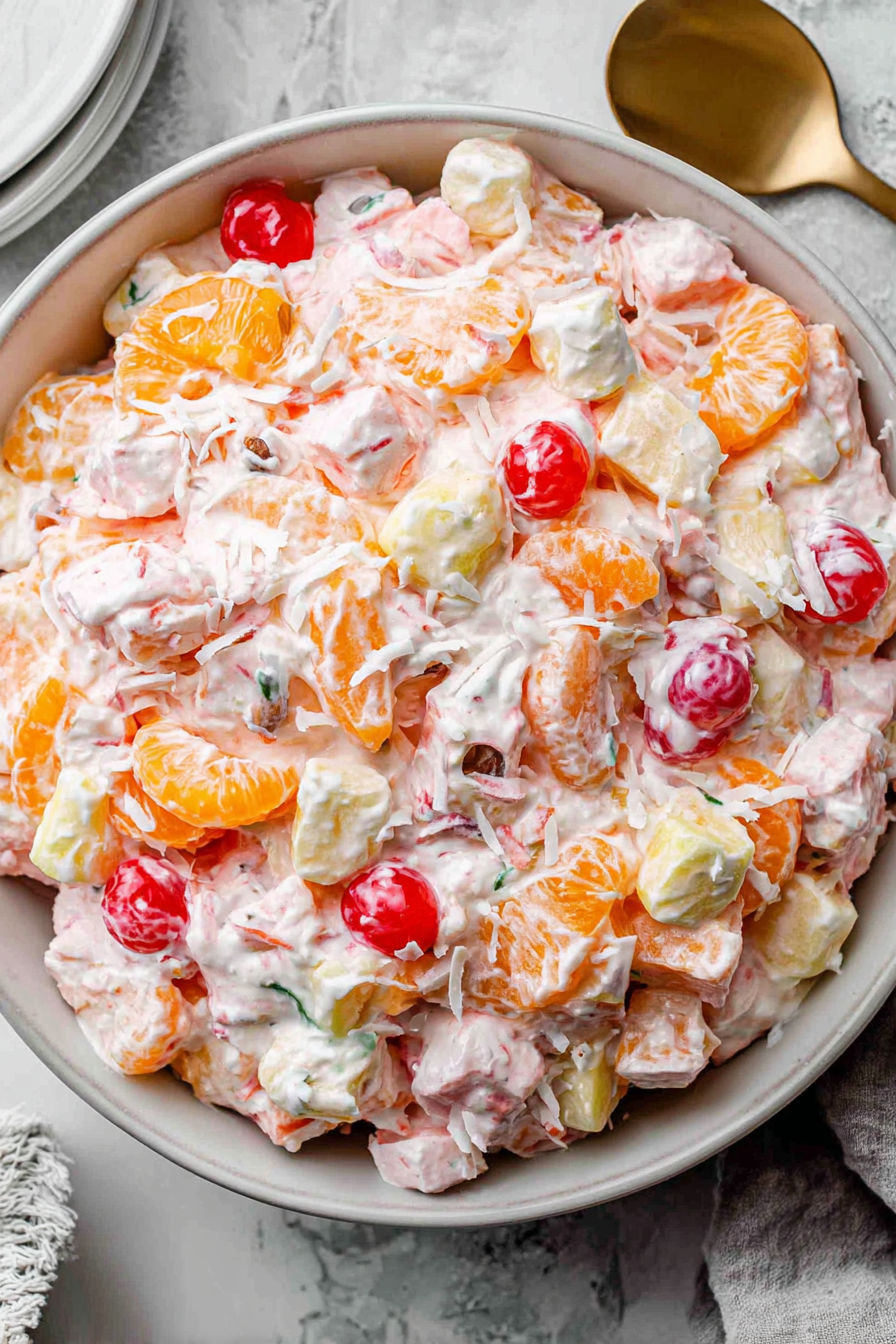 A bowl of fruit salad with oranges, strawberries, and other fruits.