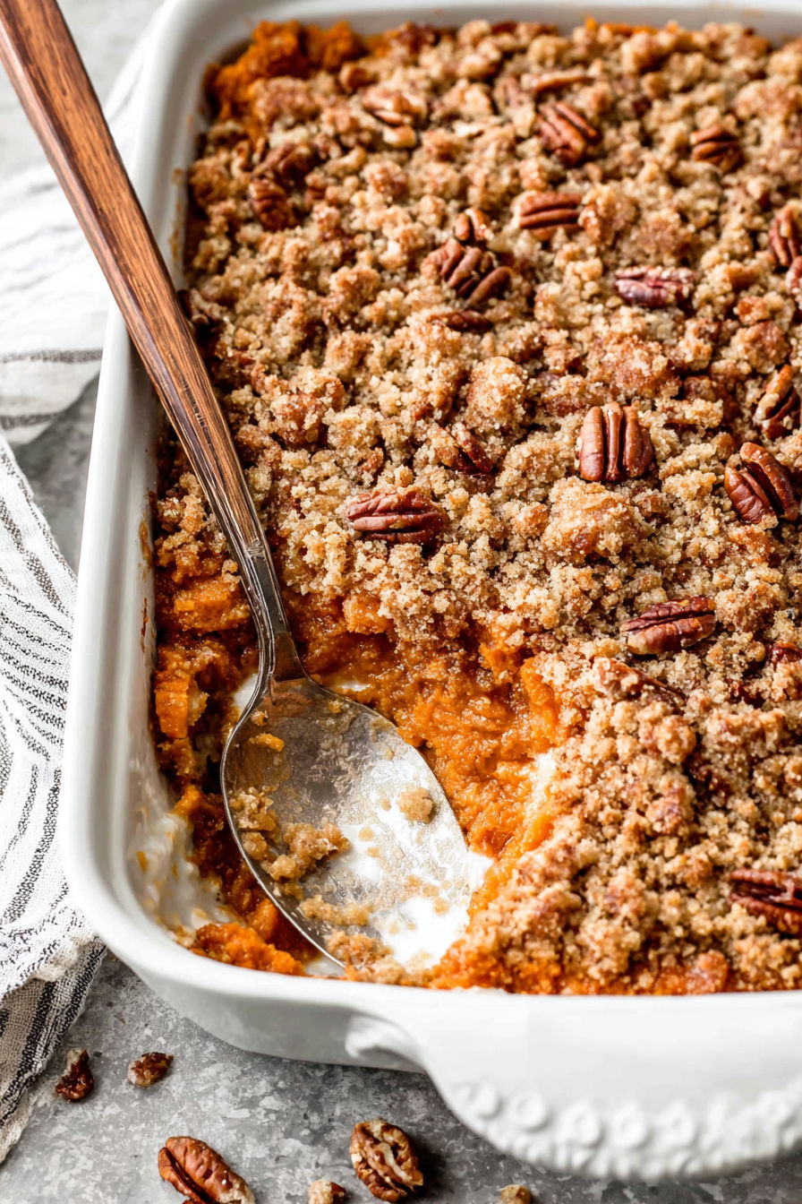 A wooden spoon in a bowl of sweet potato casserole.