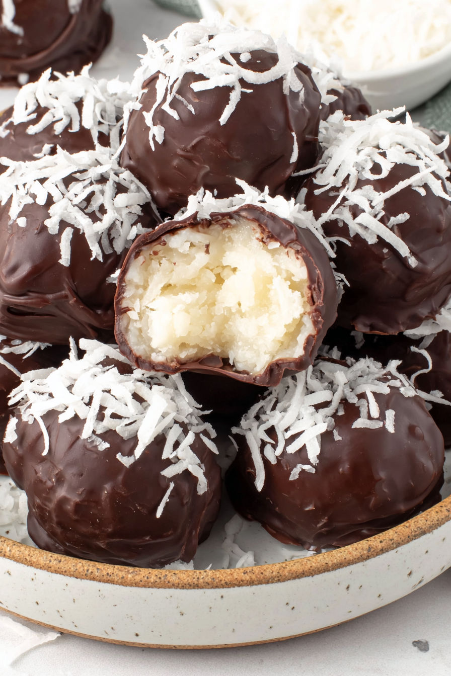 A bowl of chocolate balls with coconut on top.