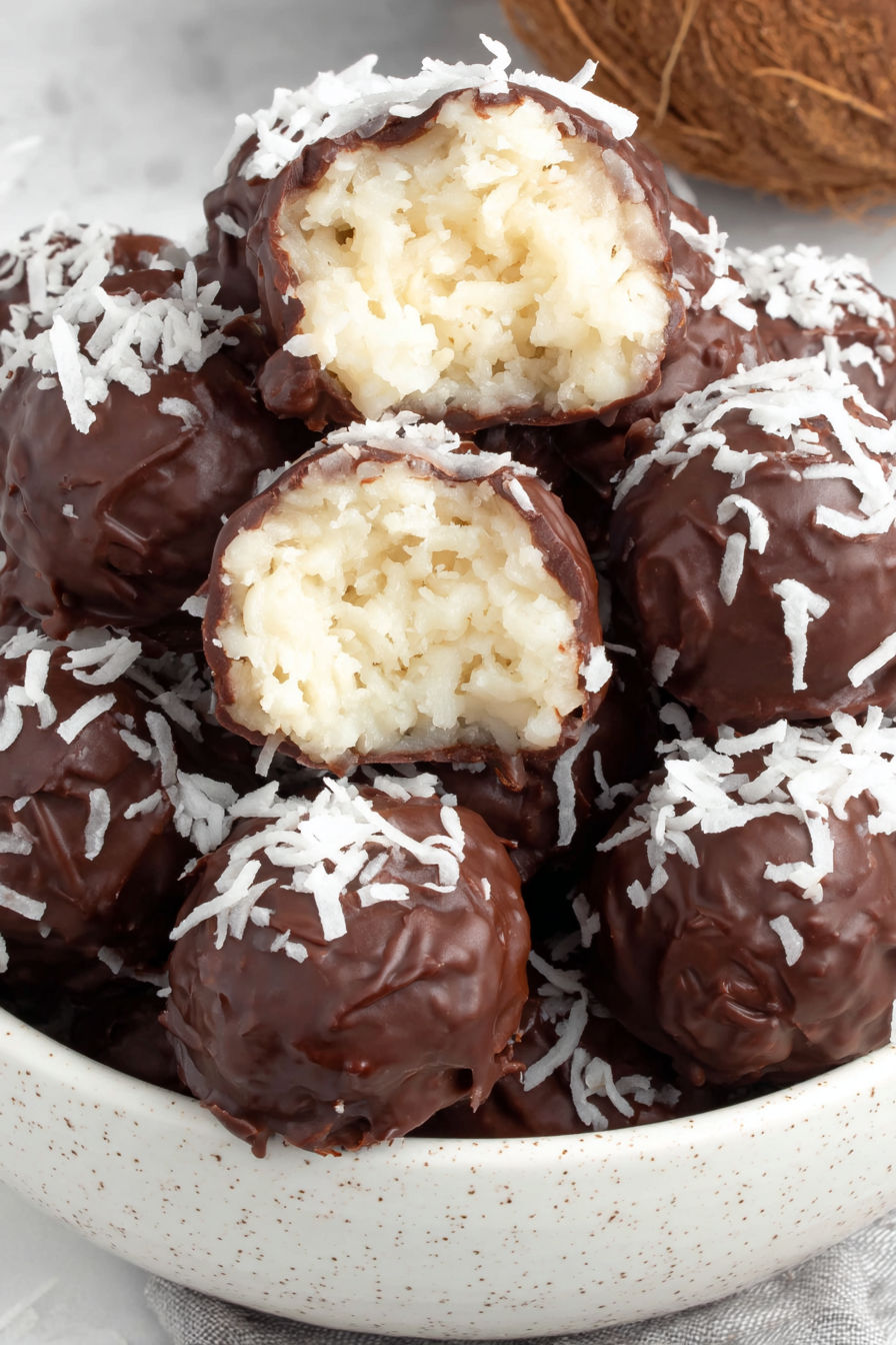 A bowl of chocolate balls with coconut on top.