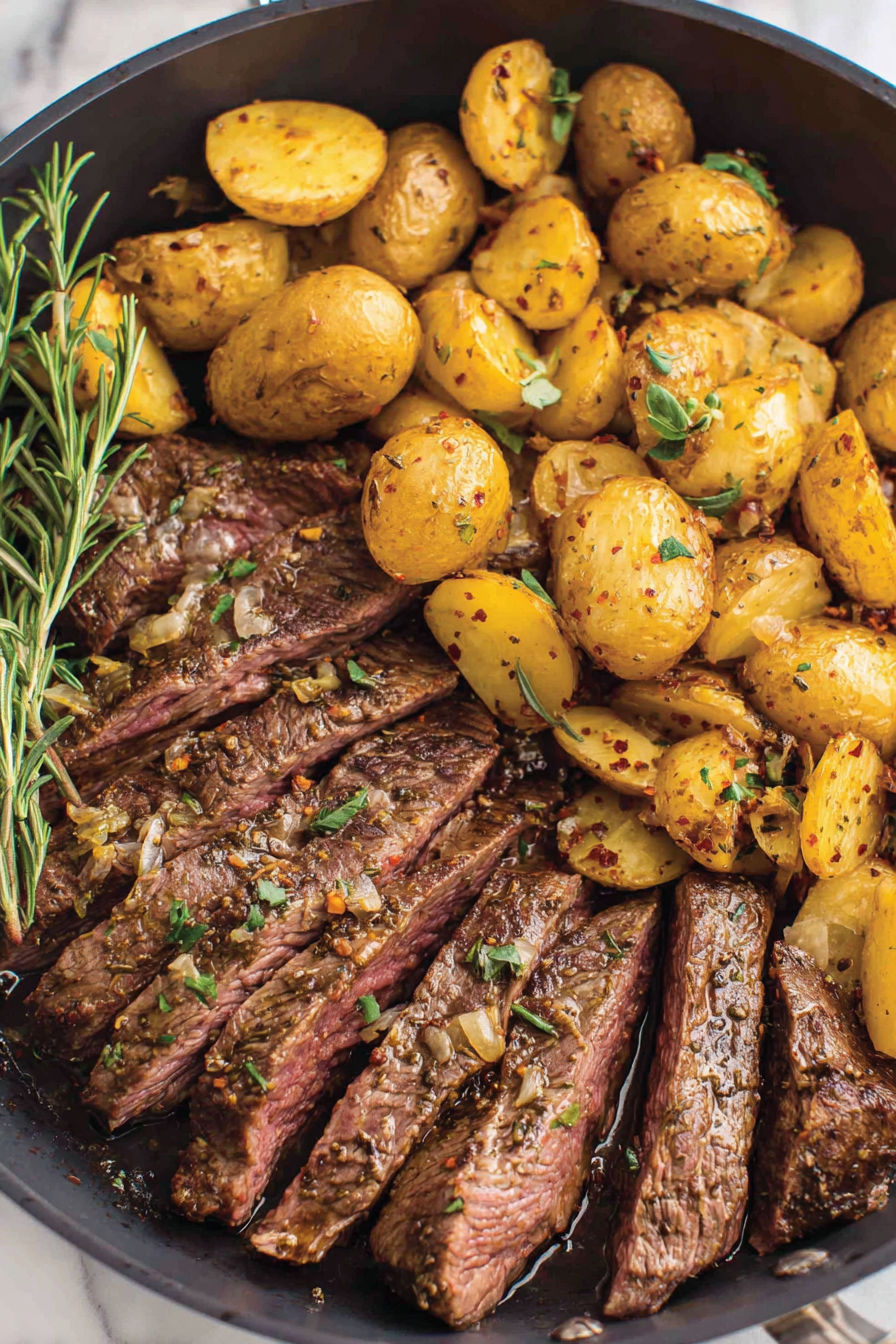 A skillet with steak and potatoes.