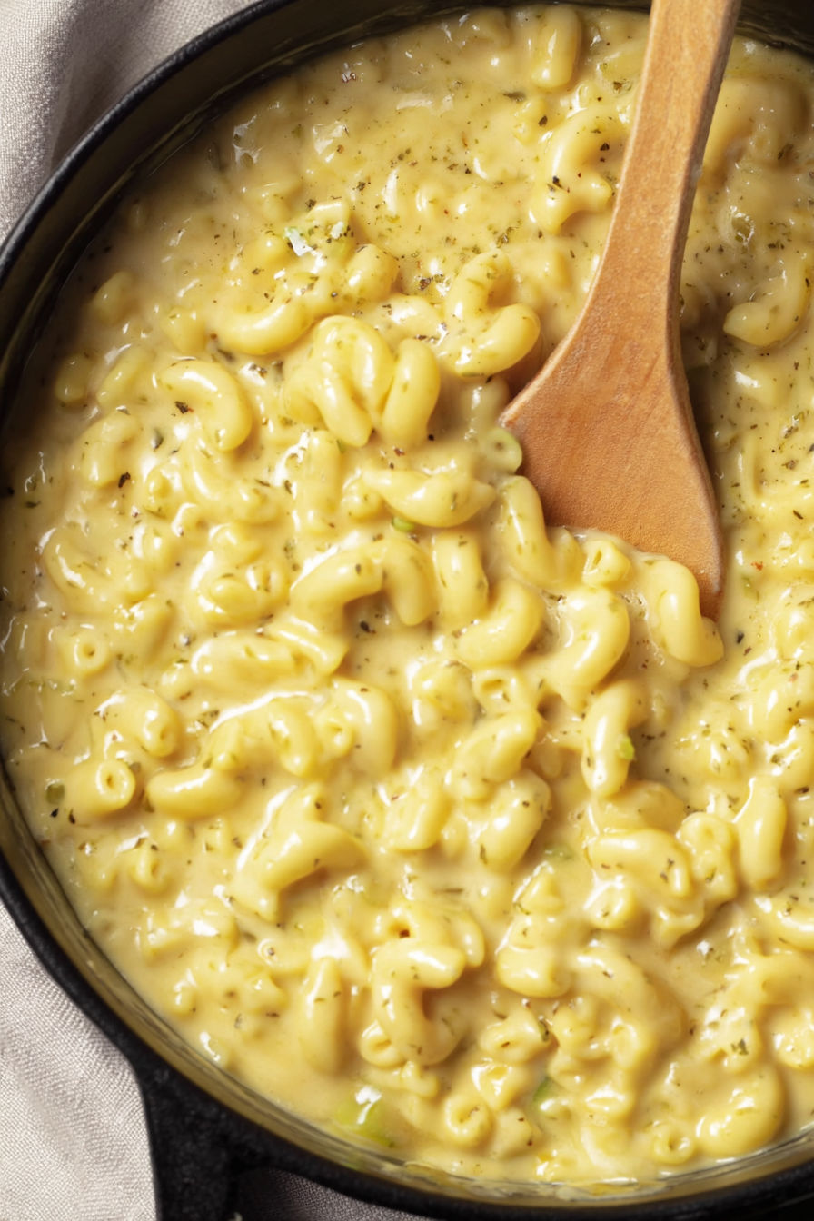 A wooden spoon in a bowl of mac and cheese.