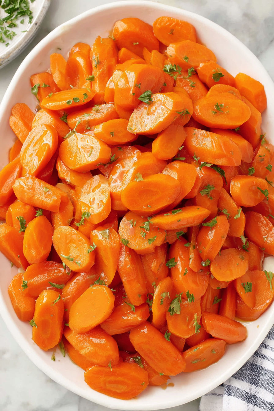 A bowl of cooked carrots with a honey glaze.