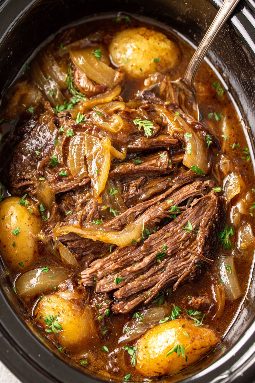 A close up of a beef stew with onions and potatoes.