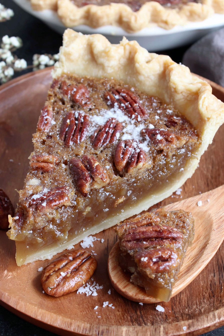 A slice of pecan pie on a wooden plate.