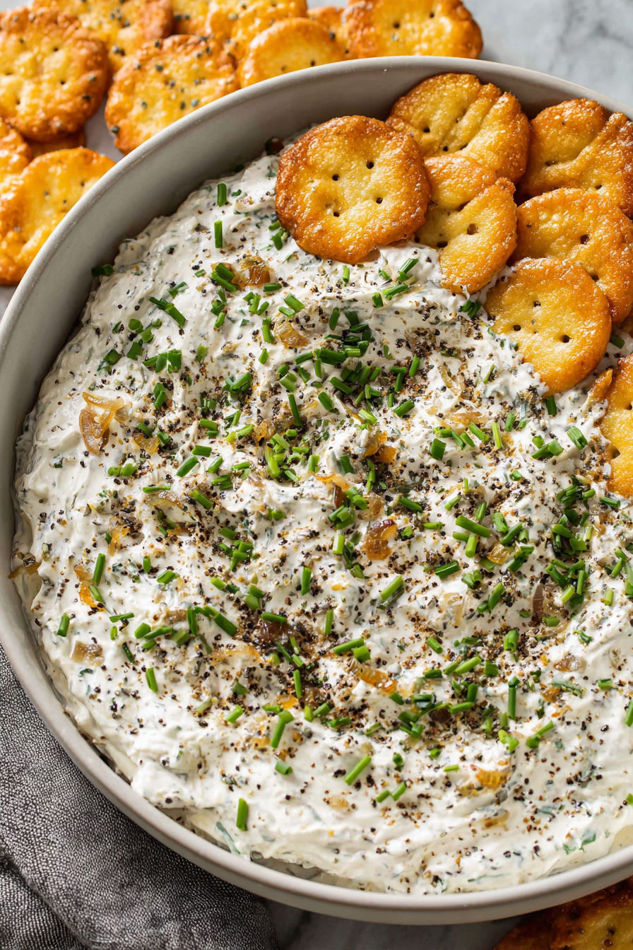 A bowl of French onion dip with crackers.