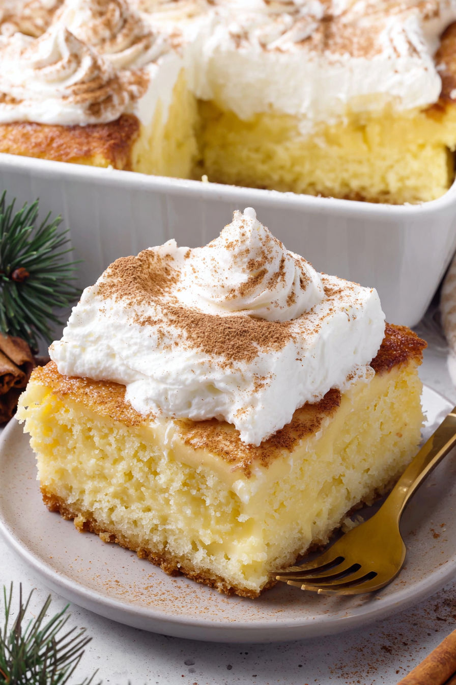 A slice of eggnog poke cake with whipped cream on top.
