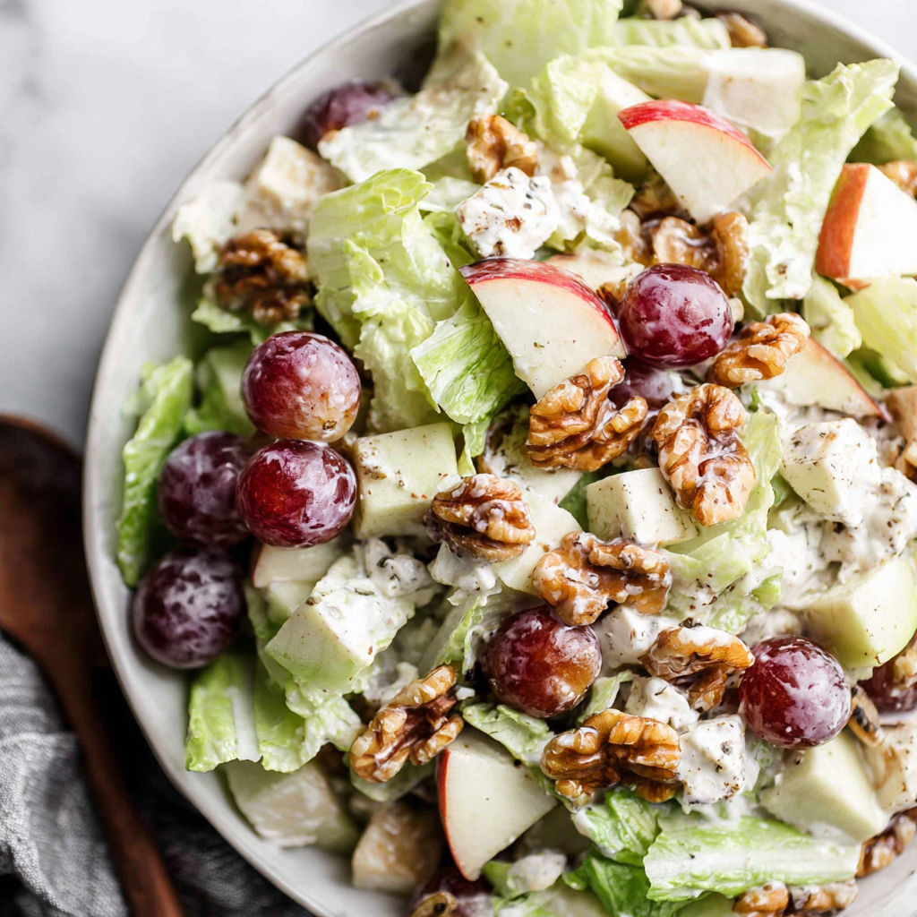 A bowl of salad with grapes, walnuts, and lettuce.