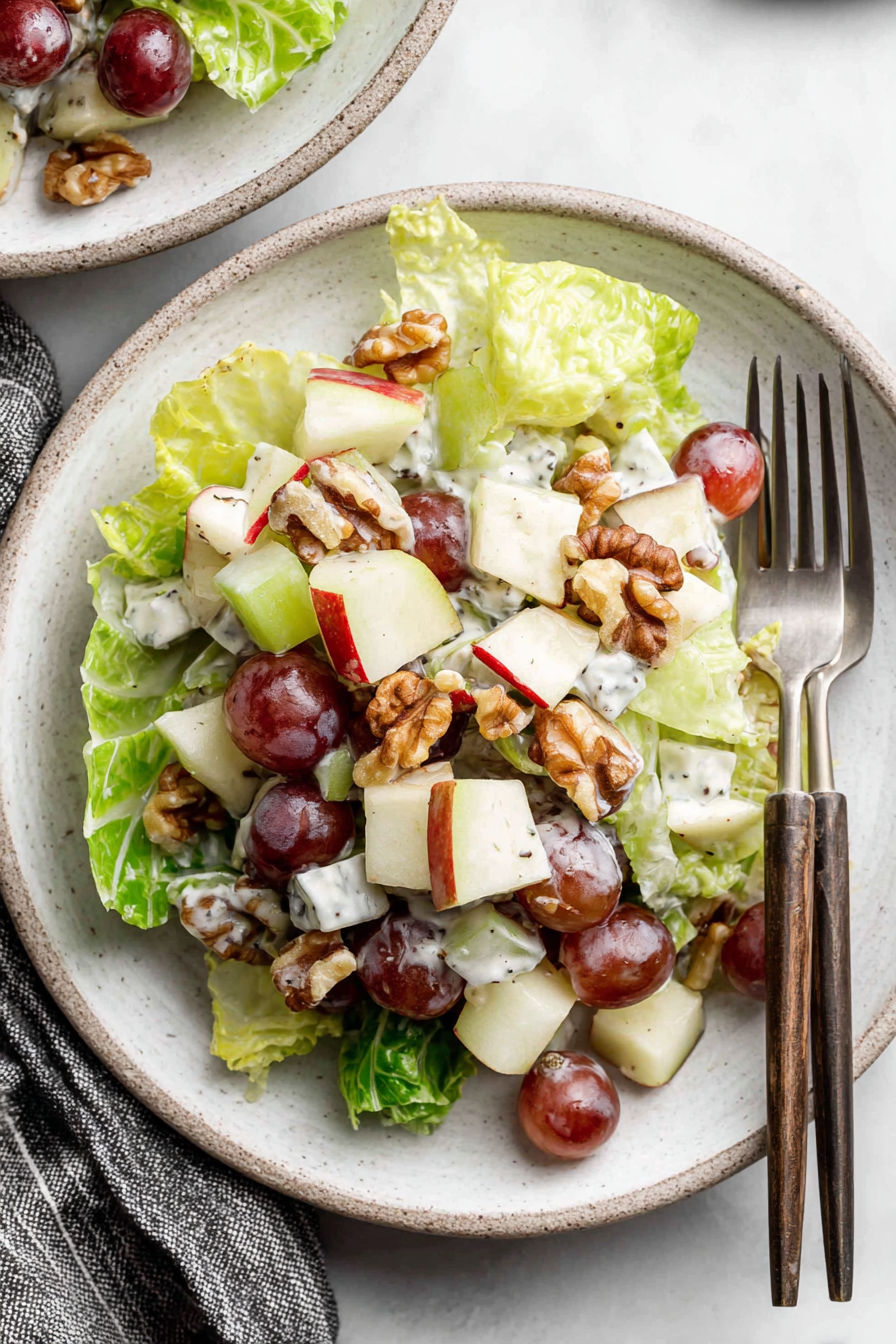 A bowl of salad with grapes, walnuts, and lettuce.
