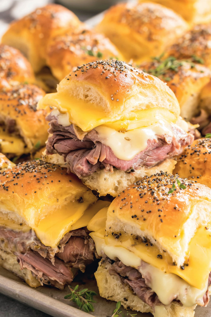 Roast beef sliders with cheese and sesame seeds.