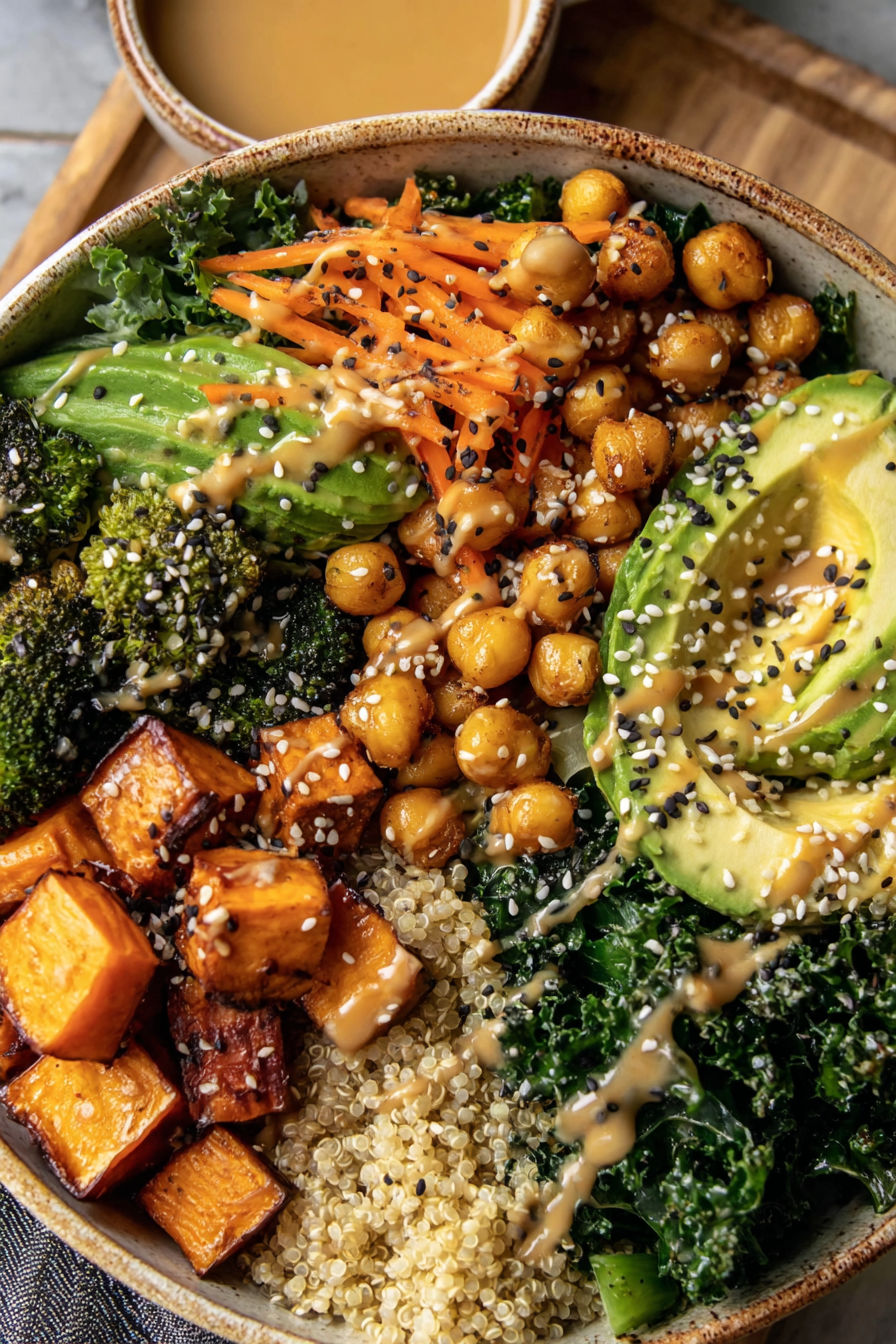 A bowl of food with a sweet potato, carrots, and avocado.