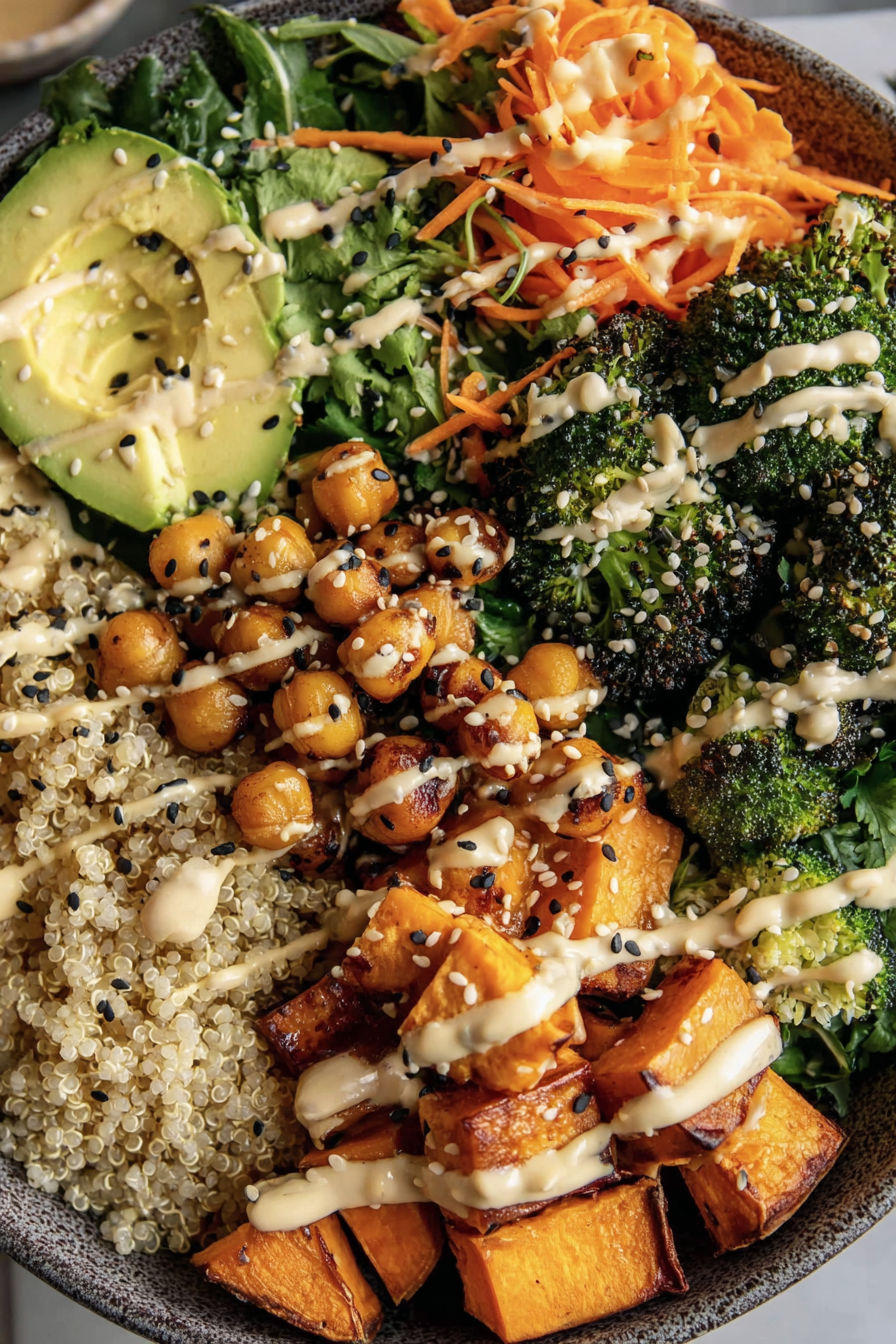 A bowl of food with a variety of ingredients, including sweet potatoes, broccoli, and carrots, all covered in a white sauce.