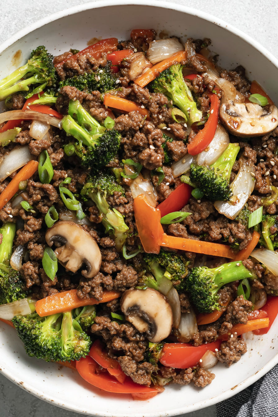 A stir fry with mushrooms, broccoli, carrots, and peppers.