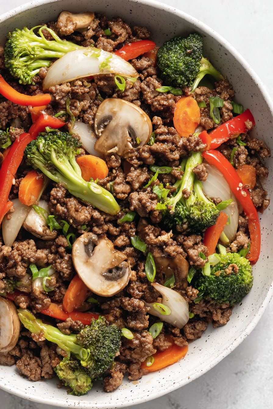A bowl of ground beef stir fry with mushrooms and broccoli.