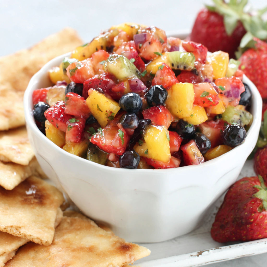 A bowl of fruit salsa with cinnamon chips.