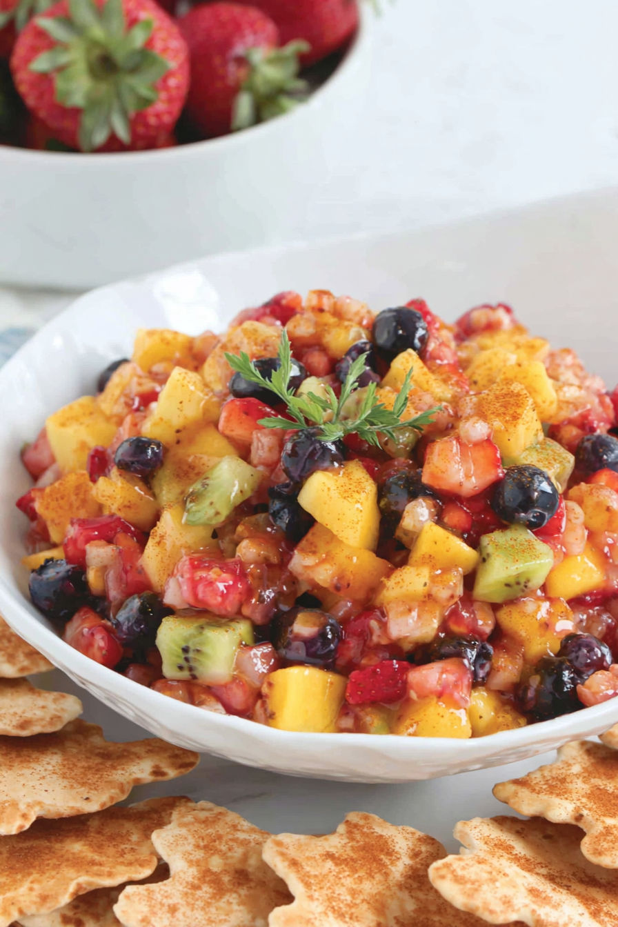 A bowl of fruit salsa with cinnamon chips.