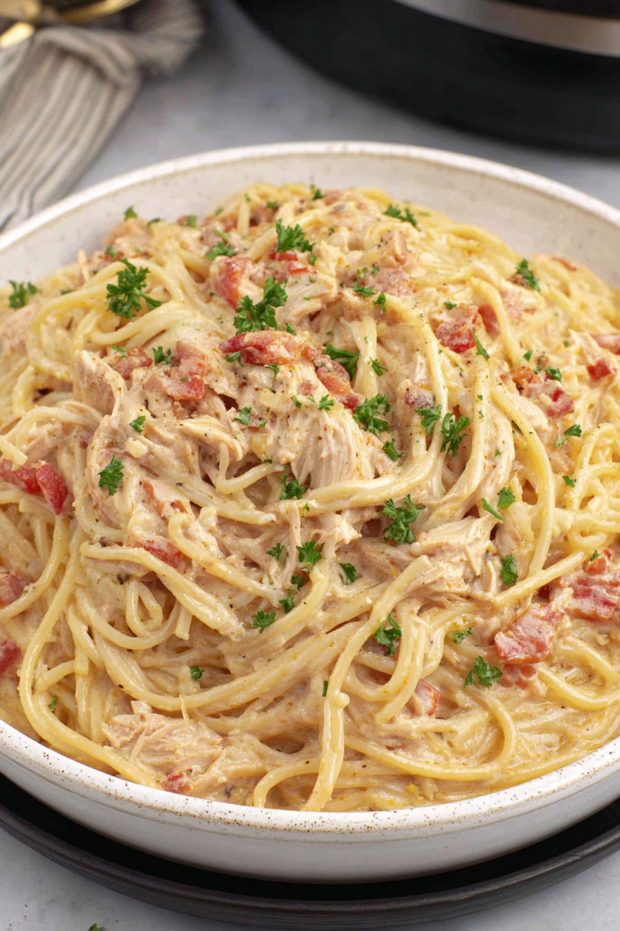 A bowl of spaghetti with chicken and tomatoes.
