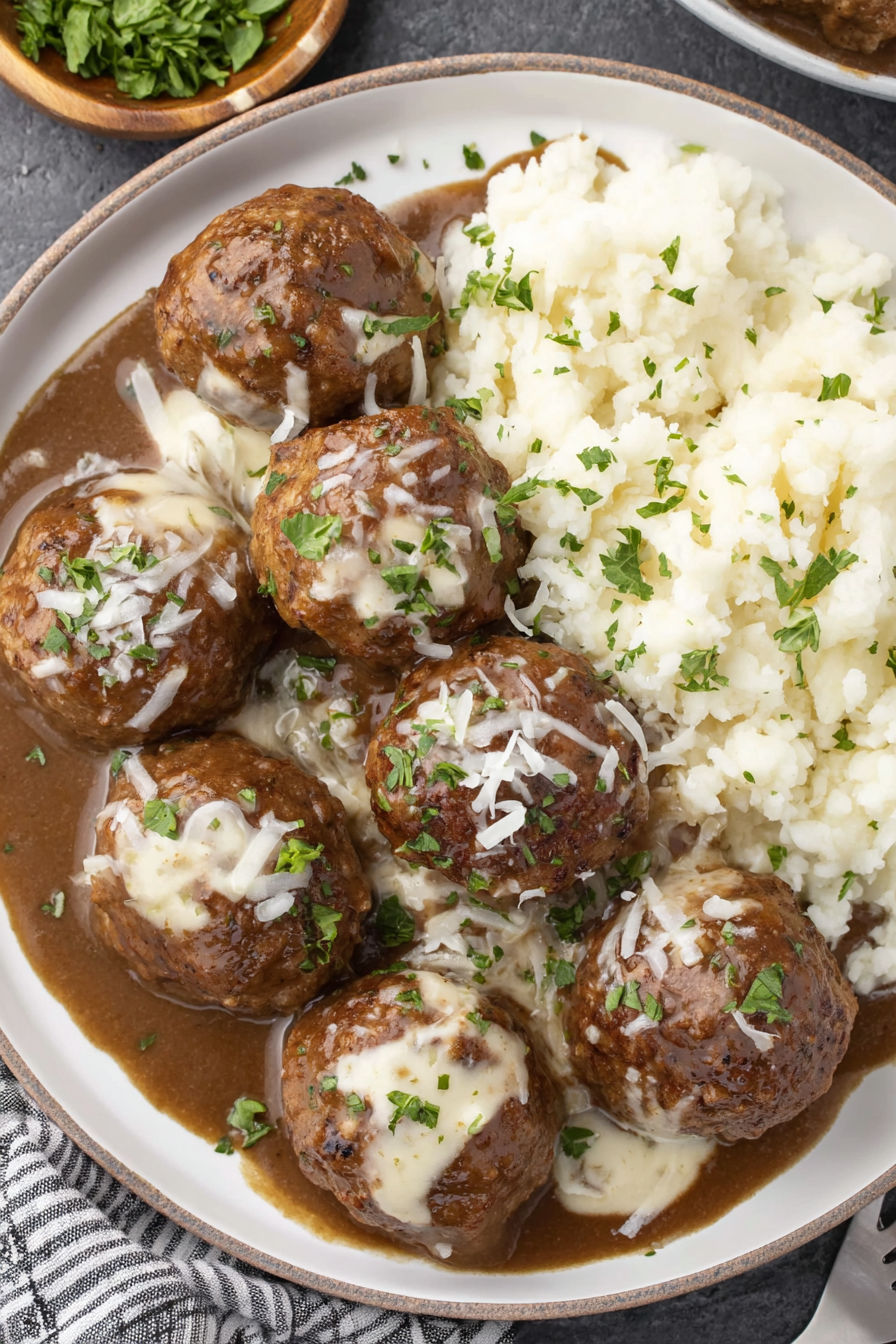 A plate of smothered meatballs with cheese and herbs.