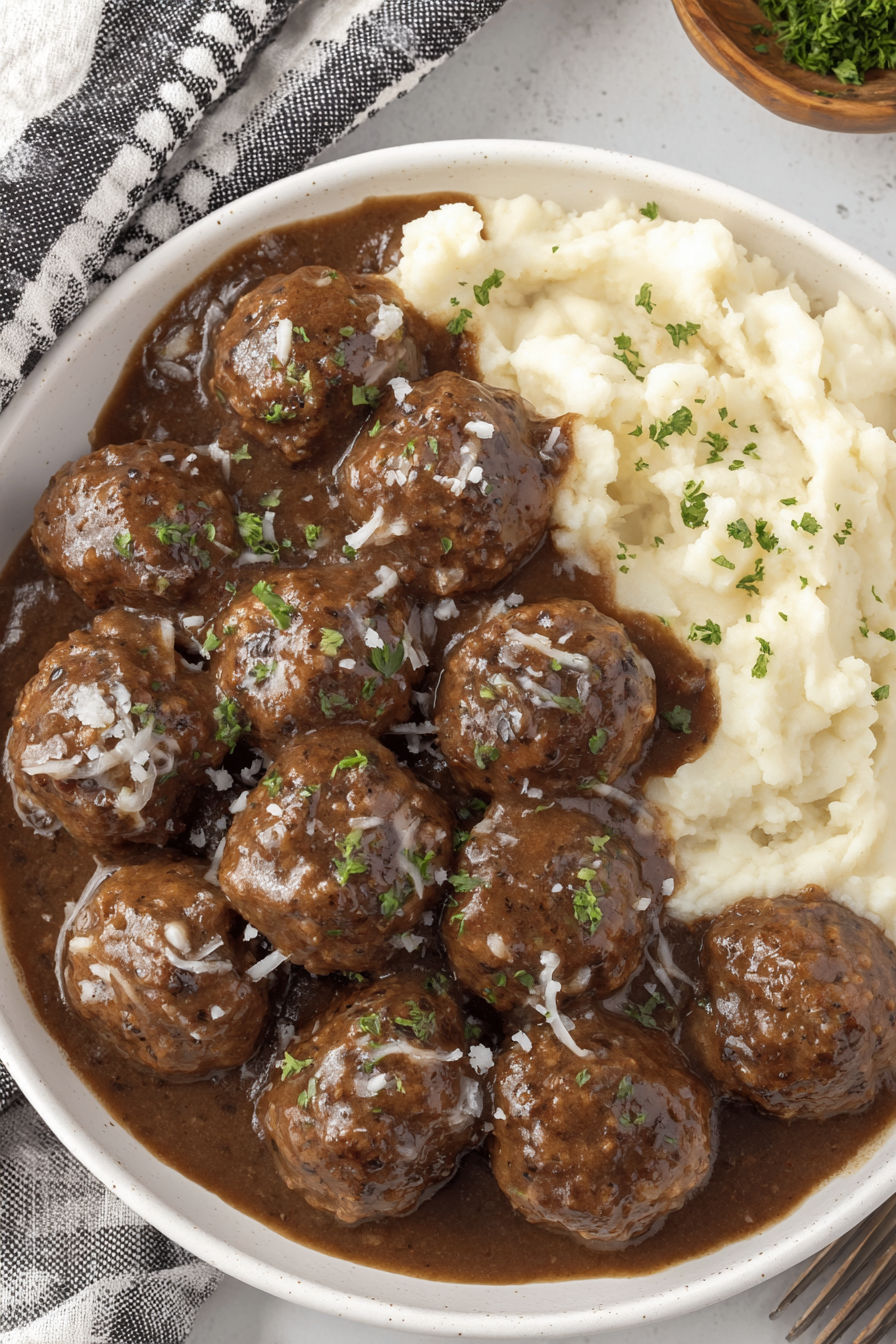 A bowl of smothered meatballs with mashed potatoes.