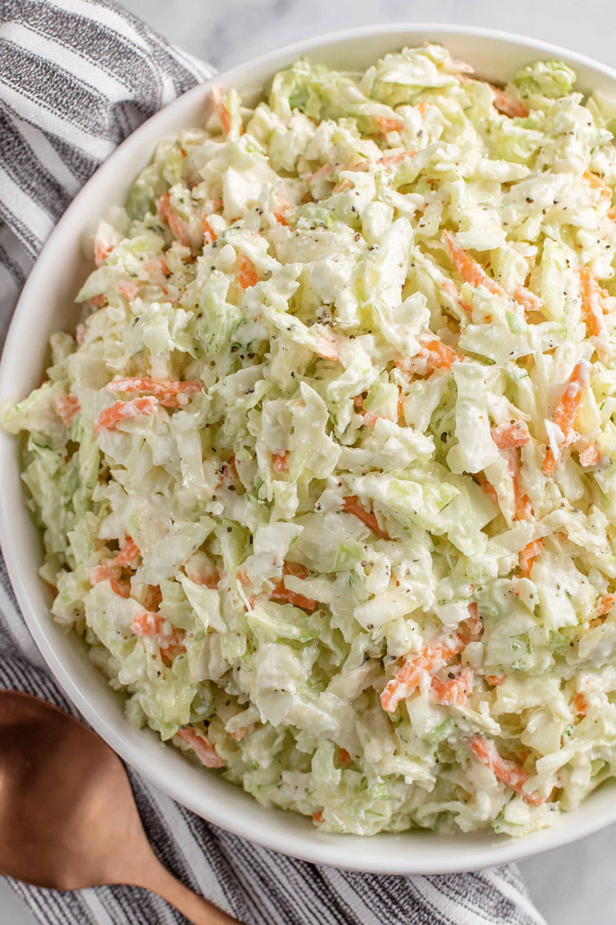 A bowl of coleslaw with carrots and cabbage.