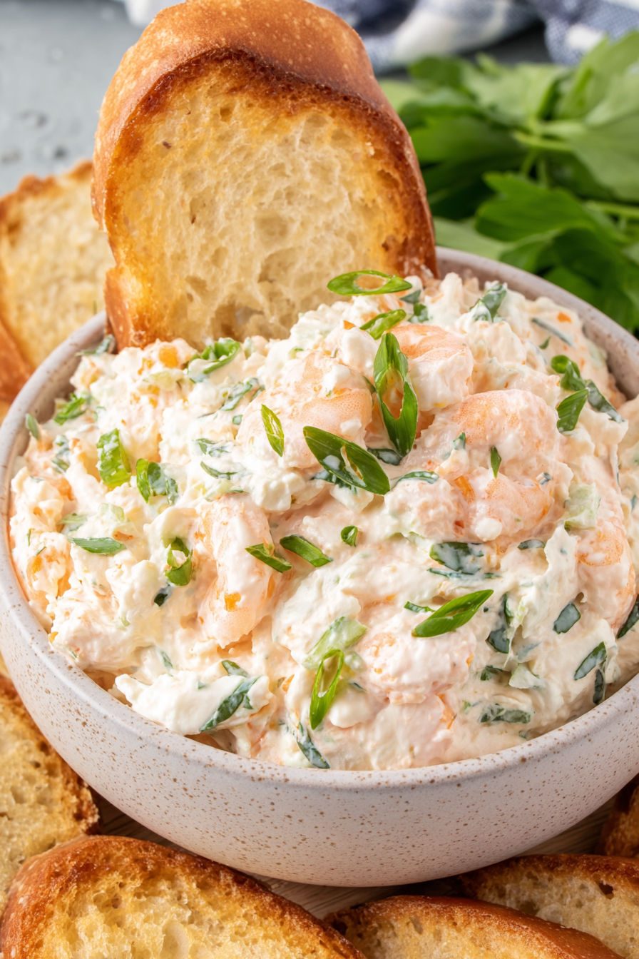 A bowl of shrimp dip with a piece of bread.