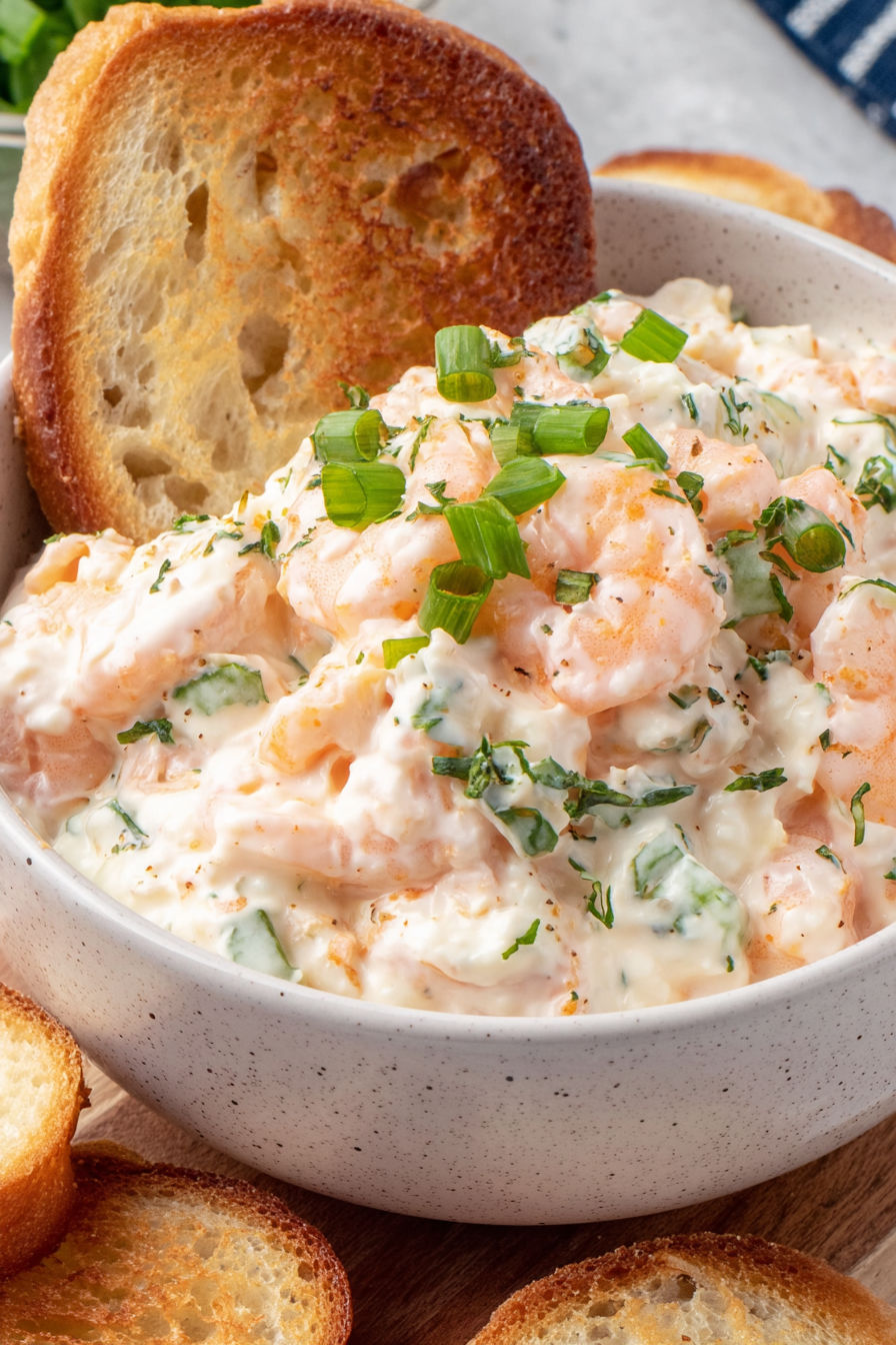 A bowl of shrimp dip with a piece of bread.