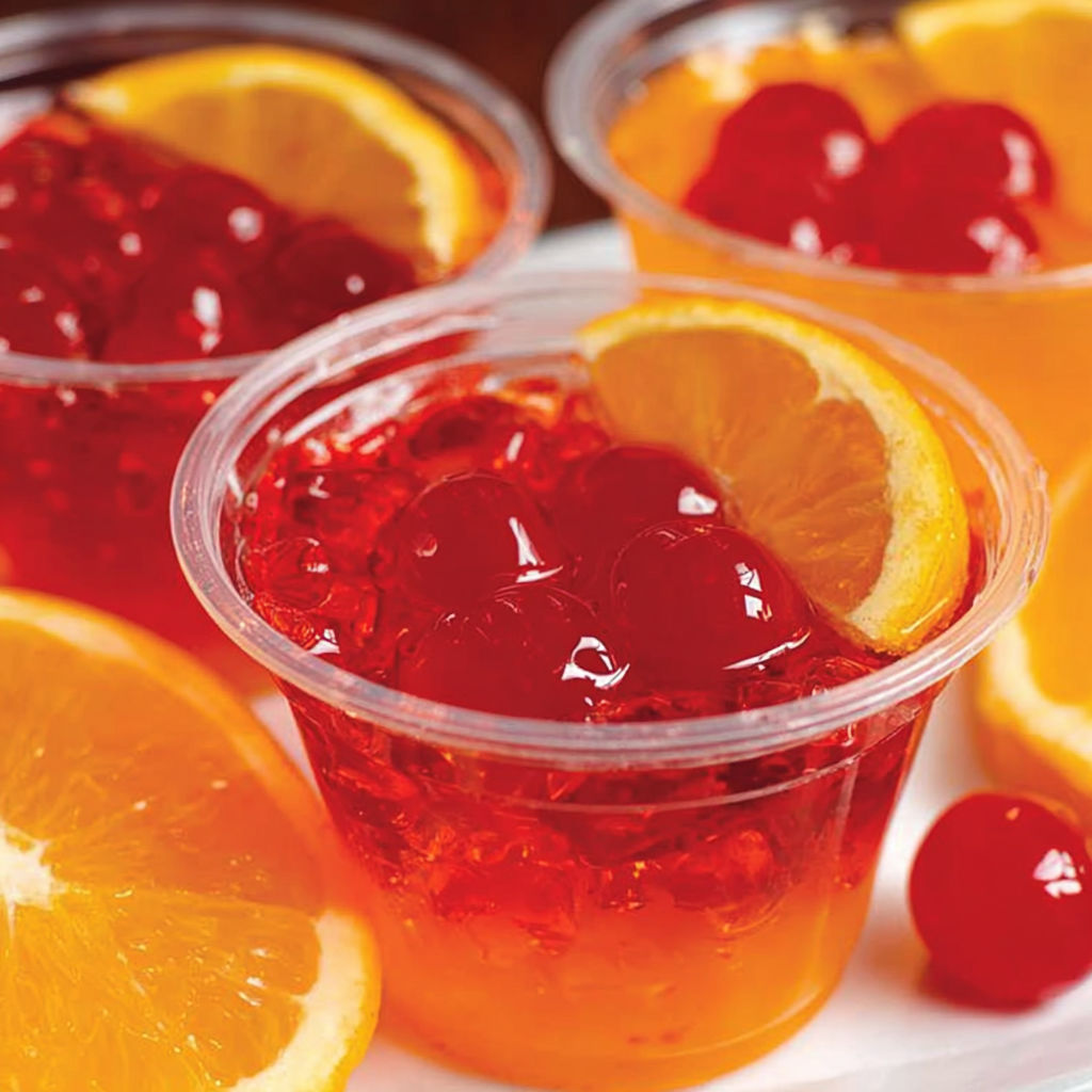 A plate of jello shots with orange slices.