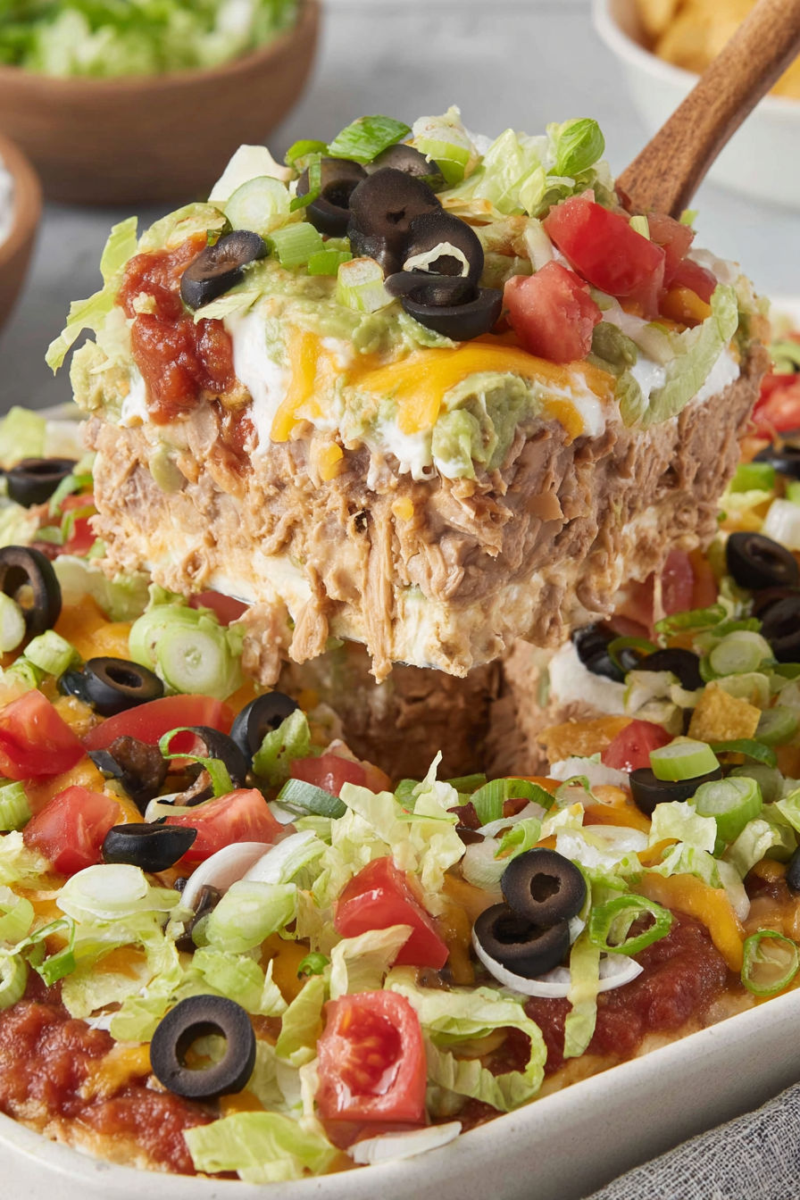 A 7 layer dip with lettuce, tomatoes, olives, and cheese.