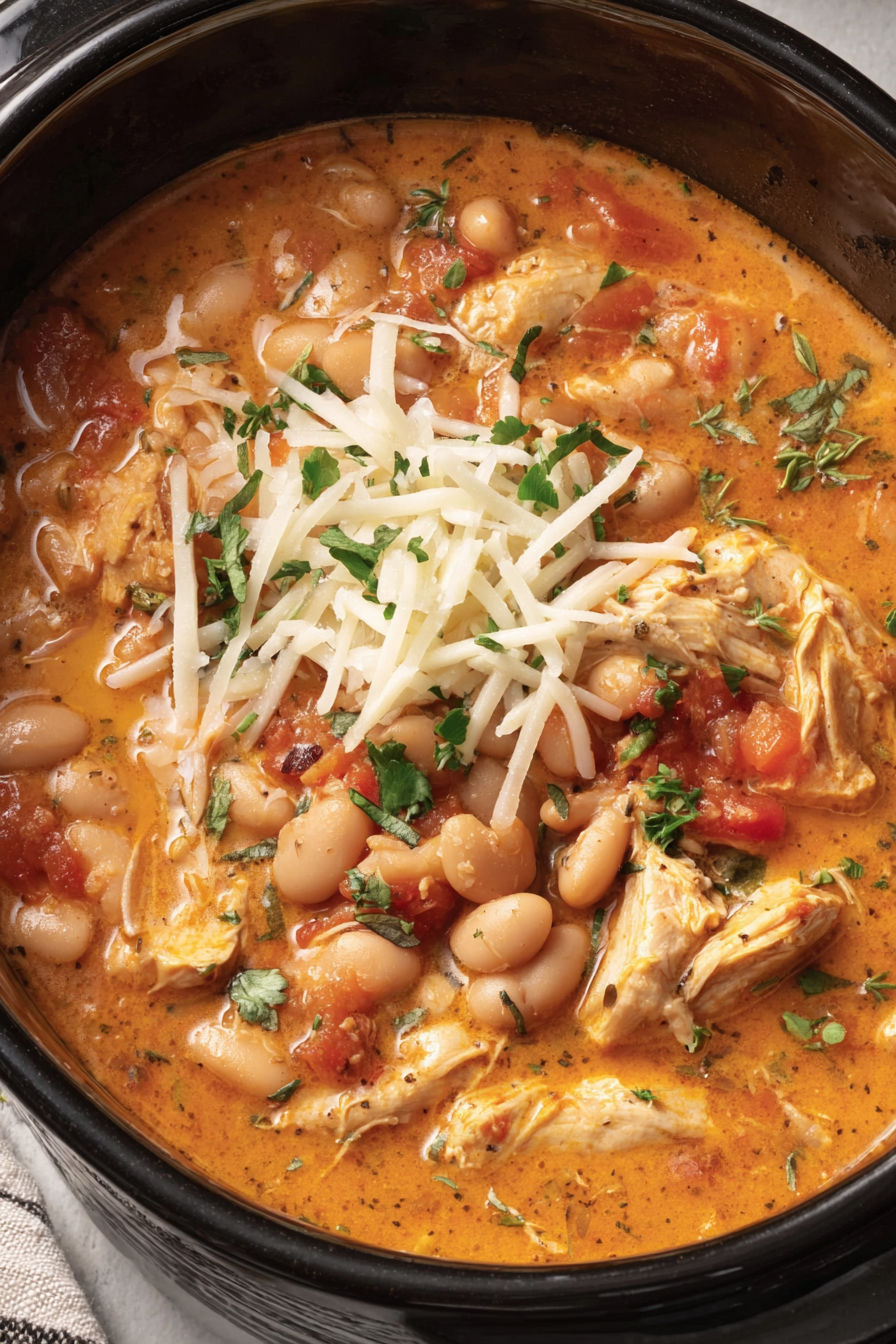 A close up of a bowl of chili with cheese on top.