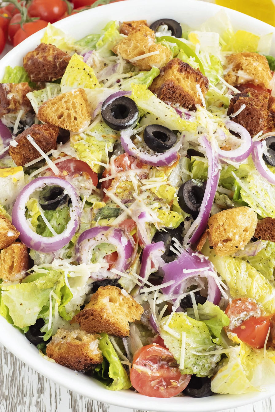 A salad with lettuce, tomatoes, olives, and croutons.
