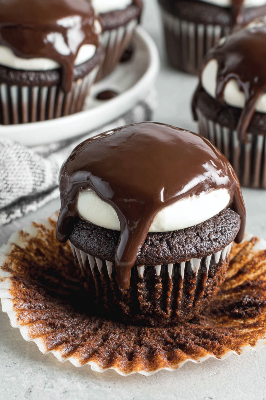 A chocolate cupcake with chocolate icing dripping off.