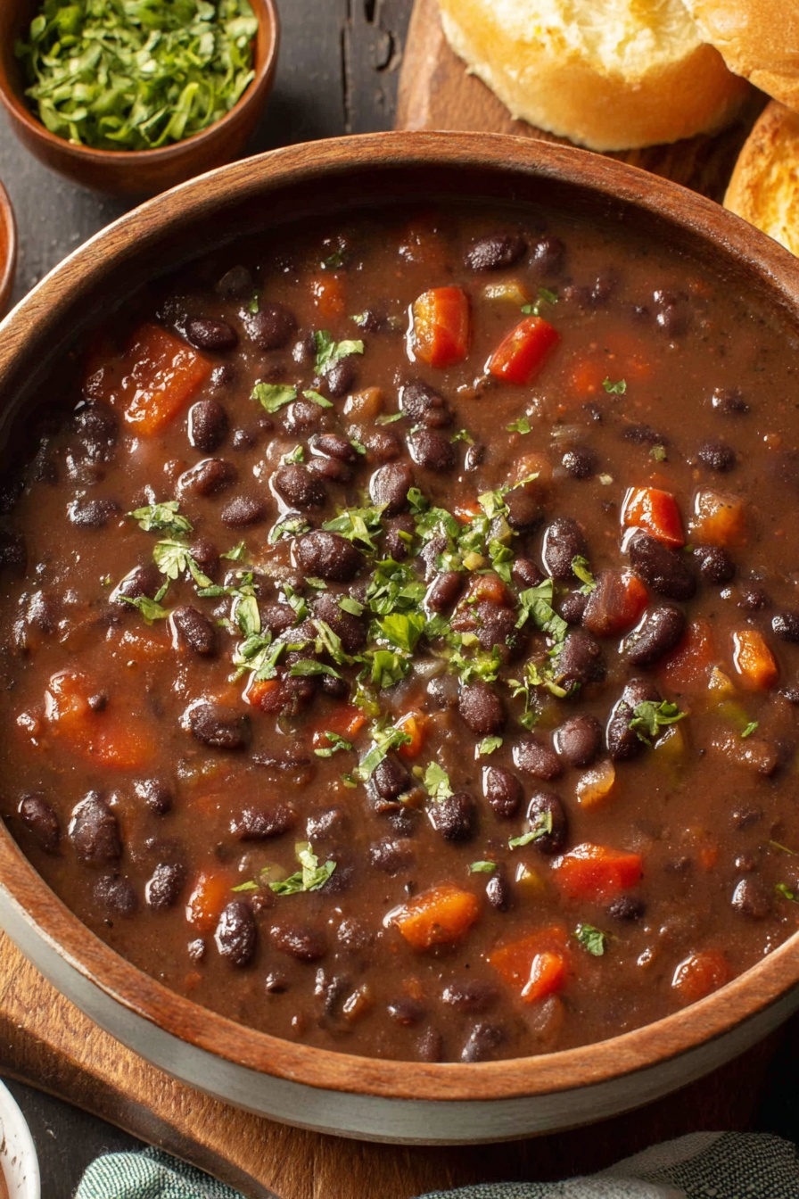 A bowl of black bean soup with a green garnish.